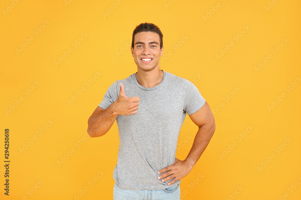 Handsome African-American man showing thumb-up on color background Handsome African-American man showing thumb-up on color background