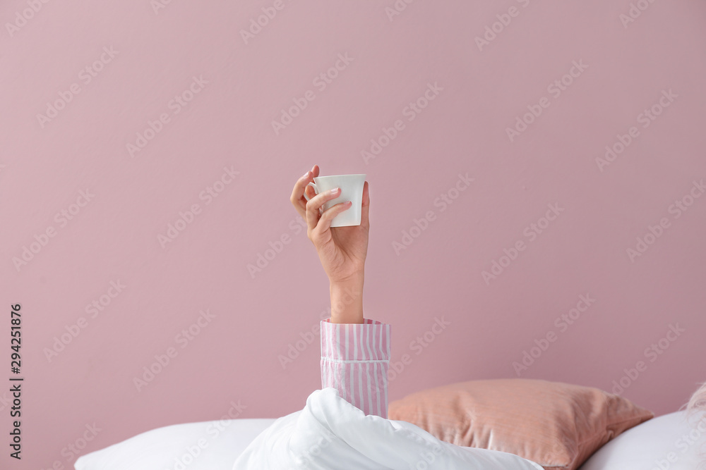 Young woman with cup of coffee lying in bed - obrazy, fototapety, plakaty 