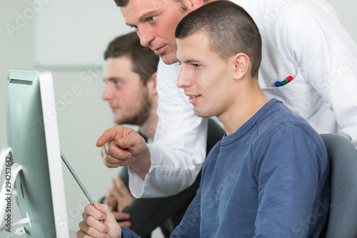 teacher with male students using computers