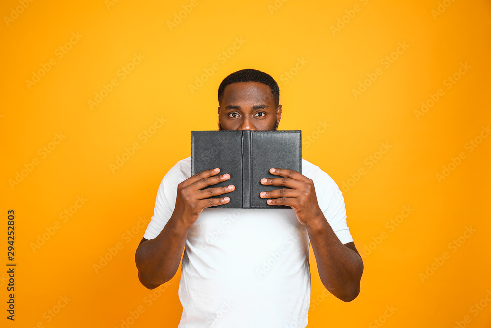 Handsome African-American man with book on color background Handsome African-American man with book on color background