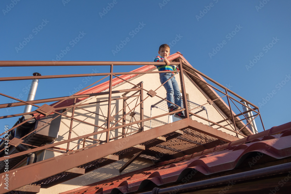 Naklejka premium A large metal staircase outside the building. The child climbed out onto the staircase railing. Danger.
