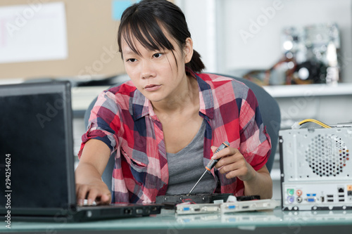 young woman fixing a desktop computer seated at a table