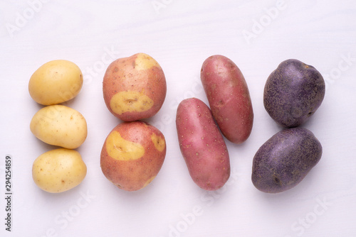 Different types of potatoes on white wooden rustic table