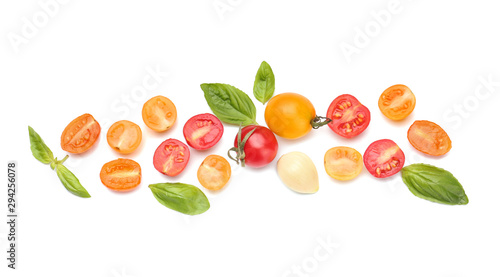 Different fresh tomatoes with basil on white background