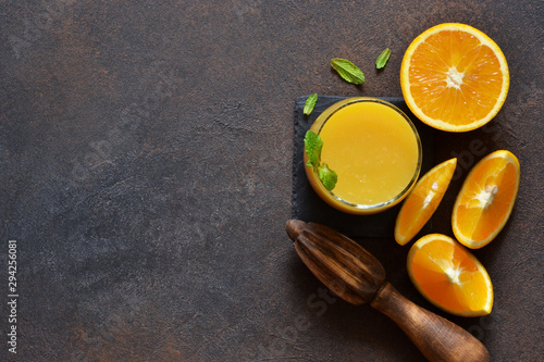 Orange juice, oranges and and juicer on stone background. Top view with copy space