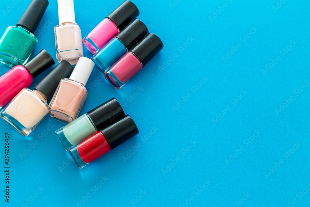 Set of colorful nail polish. Polish bottels on blue background top view copy space