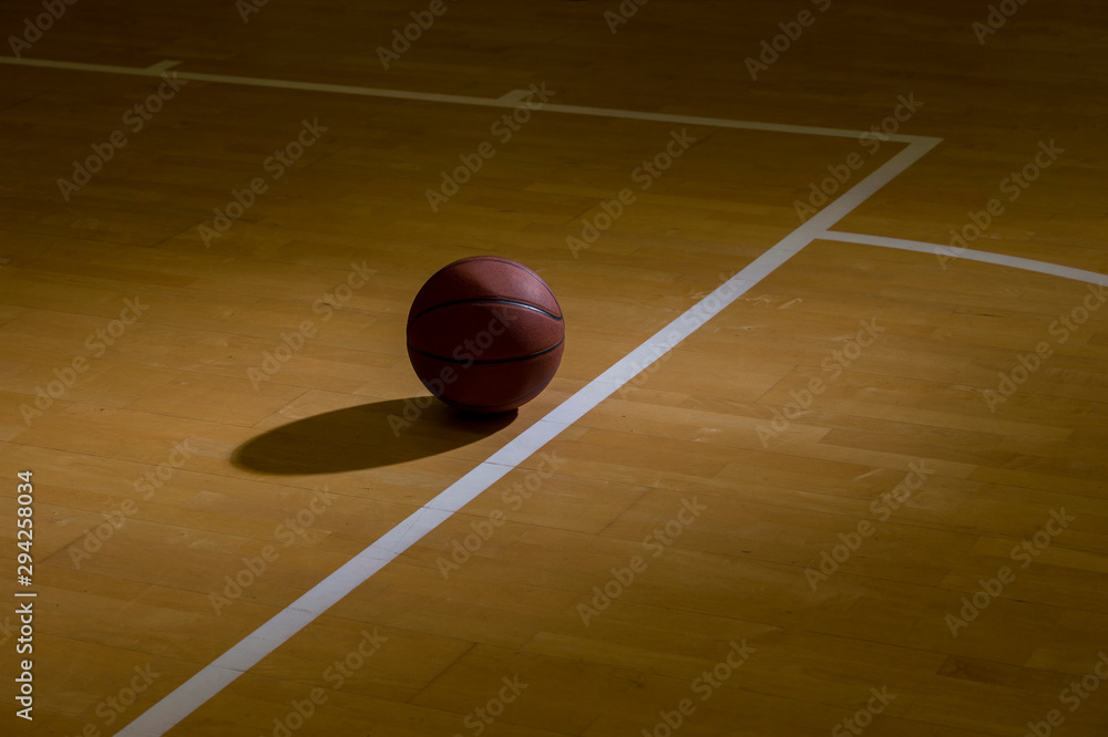 Basketball On Hardwood Court Floor With Spot Lighting - obrazy, fototapety, plakaty 