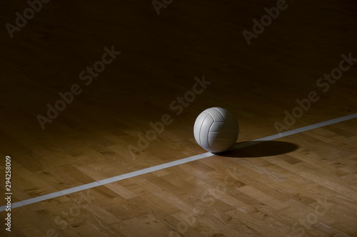 Volleyball On Hardwood Court Floor With Spot Lighting photo