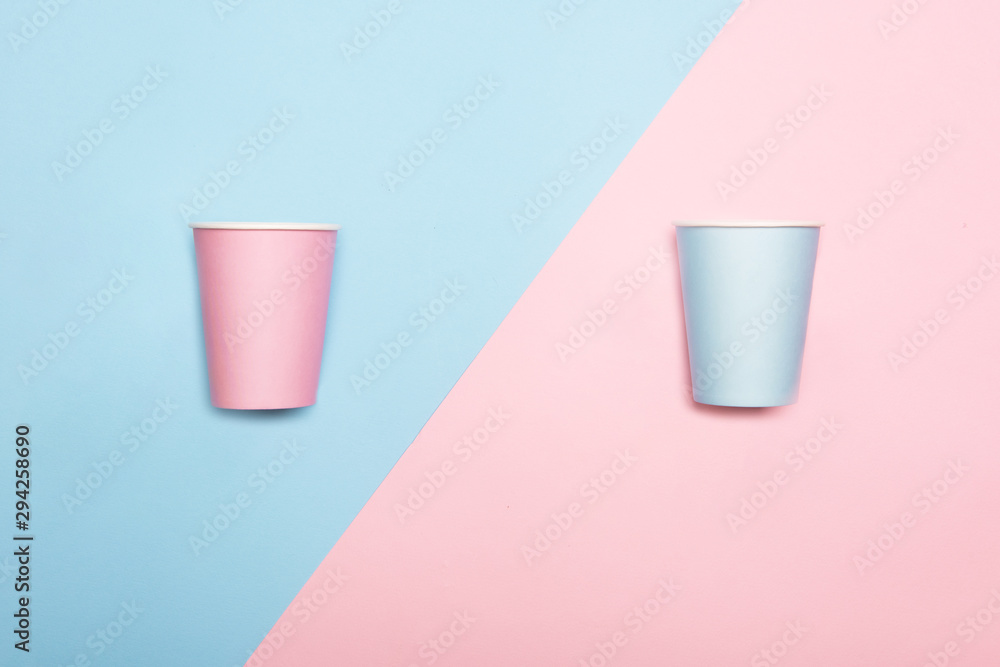 Mint blue and pink paper drinking cups on duotone pink and blue background. Birthday party celebration abstract fashion baby shower concept. Minimalist pastel style. Mint blue and pink paper drinking cups on duotone pink and blue background. Birthday party celebration abstract fashion baby shower concept. Minimalist pastel style.