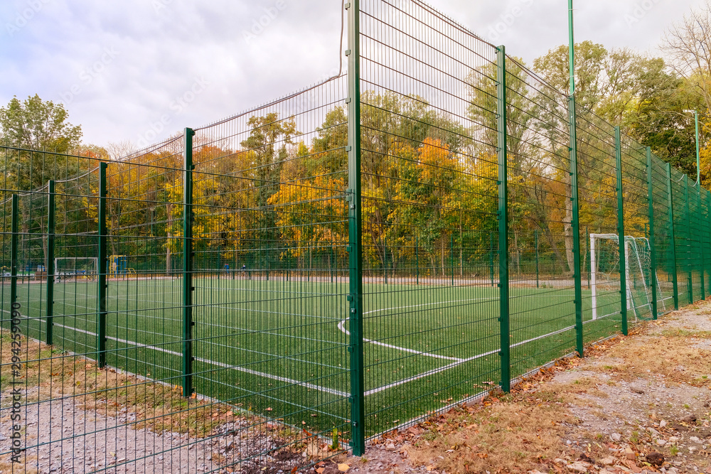 Mini-football court fenced with a green fence in autumn day Mini-football court fenced with a green fence in autumn day