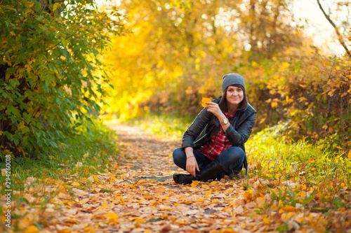 Girl sitting in autumn park among yellow autumn leaves