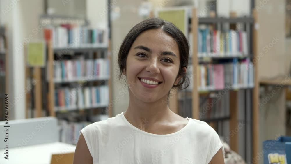 Beautiful Asian woman wearing white blouse standing at library. Front view of smiling lady looking at camera. Female beauty concept Beautiful Asian woman wearing white blouse standing at library. Front view of smiling lady looking at camera. Female beauty concept