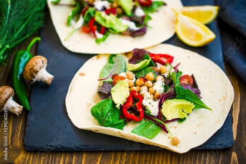 Vegan wraps with salad, avocado, pepper, tomatoes, chickpeas and garlic sauce