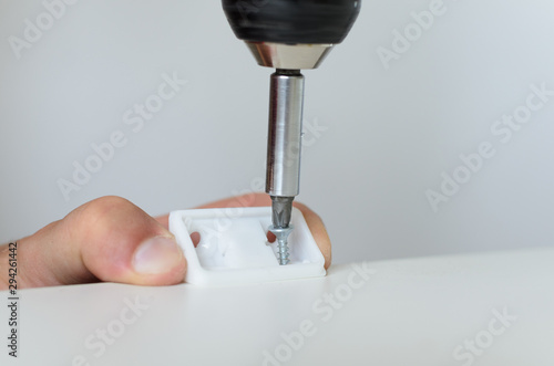 worker fastens detail when assembling white furniture photo