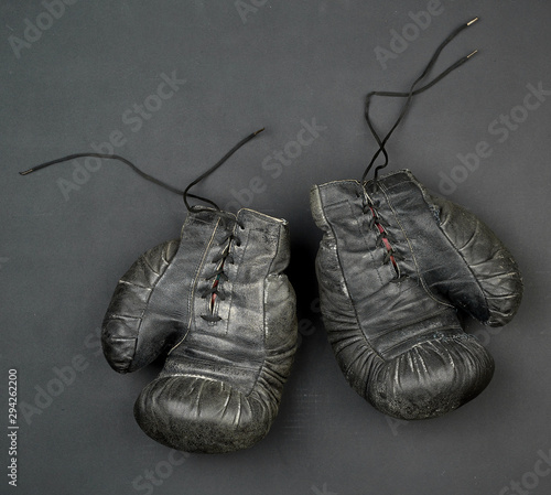 pair of black leather very old boxing gloves on a black background