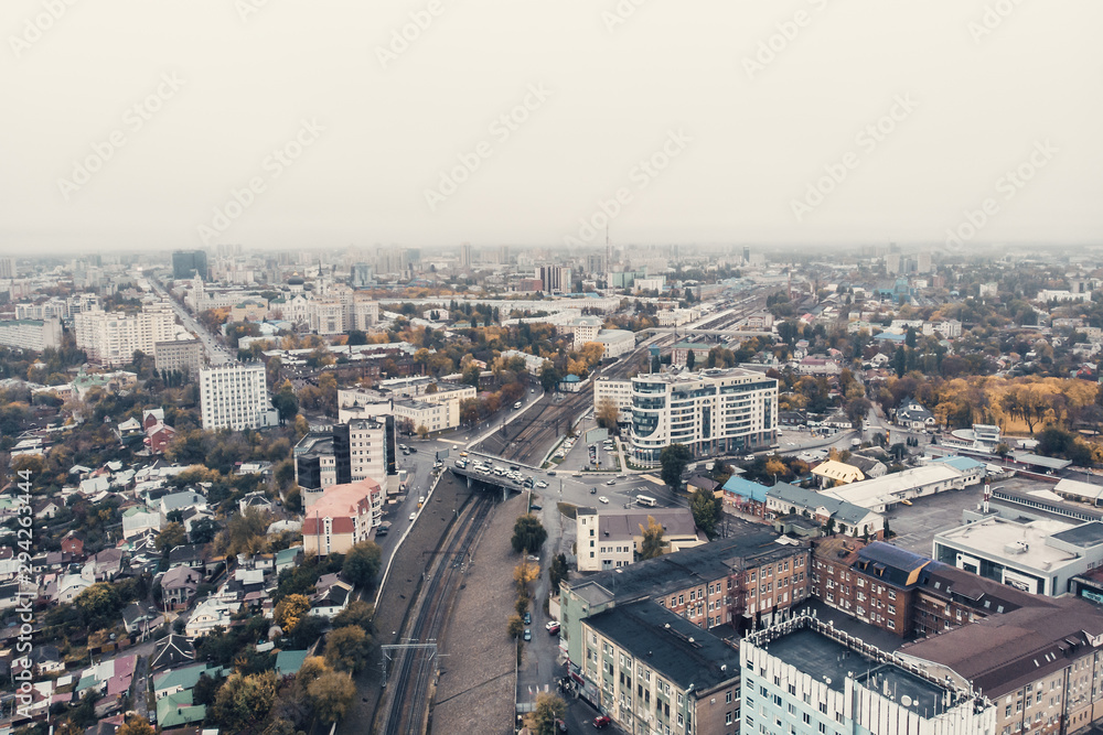 Aerial view camera flight above autumn city in foggy weather with many buildings and roads with car traffic