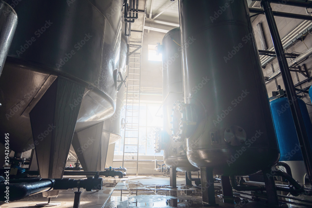 Industrial interior of water plant production. Steel tanks or valves for filtration of water and pipeline Industrial interior of water plant production. Steel tanks or valves for filtration of water and pipeline