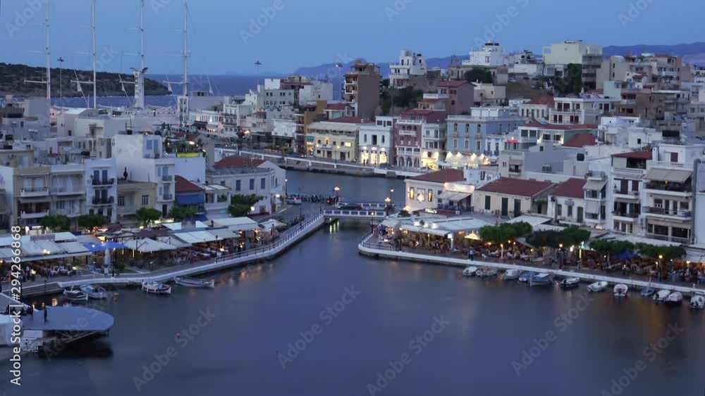 Beautiful sunset at Agios Nikolaos city, Port at Aegean sea. Crete,Greece. Peaceful harbor of Voulismeni Lake. Long promenade with restaurants. Panoramic view of seaport with yachts and boats at quay Beautiful sunset at Agios Nikolaos city, Port at Aegean sea. Crete,Greece. Peaceful harbor of Voulismeni Lake. Long promenade with restaurants. Panoramic view of seaport with yachts and boats at quay