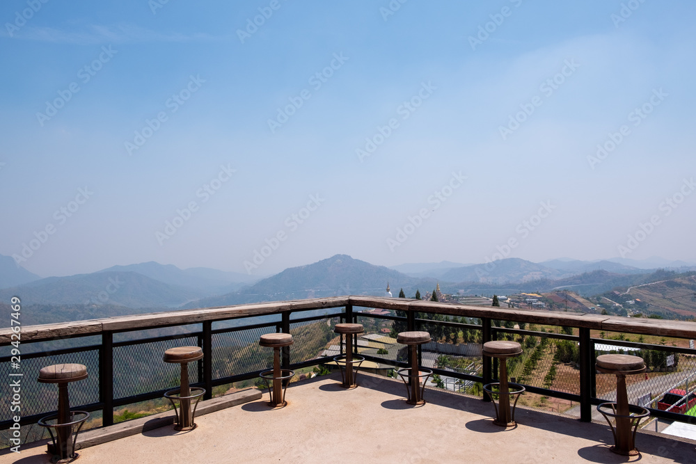 Rows of wooden stools and counter bar on outdoor terrace. Relaxing seat, mountain viewpoint outside the building.