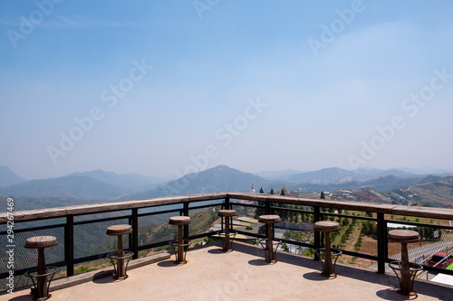 Rows of wooden stools and counter bar on outdoor terrace. Relaxing seat, mountain viewpoint outside the building.