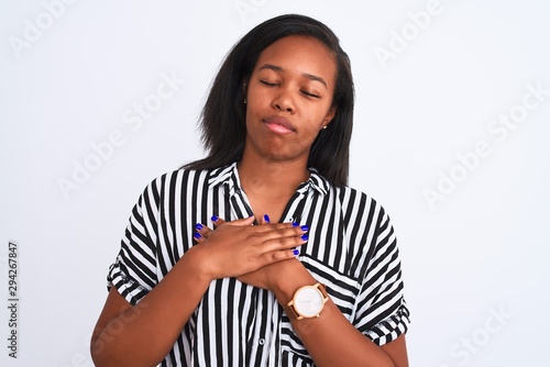 Beautiful young african american woman wearing elegant shirt over isolated background smiling with hands on chest with closed eyes and grateful gesture on face. Health concept.