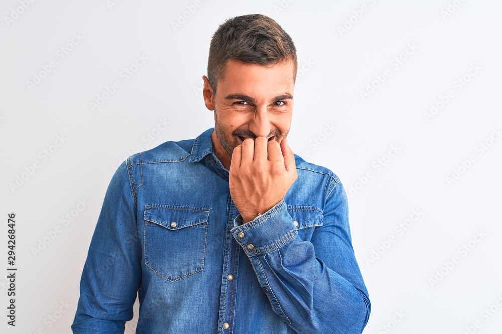 Young handsome man wearing denim jacket standing over isolated background looking stressed and nervous with hands on mouth biting nails. Anxiety problem. Young handsome man wearing denim jacket standing over isolated background looking stressed and nervous with hands on mouth biting nails. Anxiety problem.