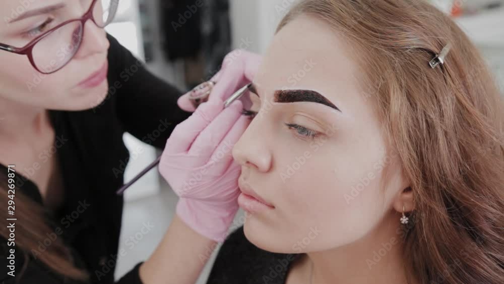 Professional makeup artist paints eyebrows to client with henna. Professional makeup artist paints eyebrows to client with henna.