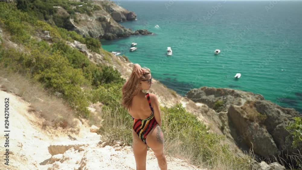 Young adult woman in swimsuit looking at sea Young adult woman in swimsuit looking at sea