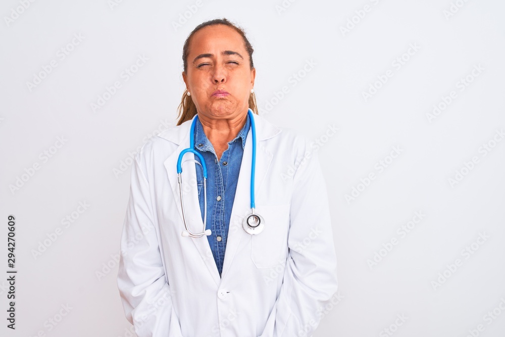 Middle age mature doctor woman wearing stethoscope over isolated background puffing cheeks with funny face. Mouth inflated with air, crazy expression. Middle age mature doctor woman wearing stethoscope over isolated background puffing cheeks with funny face. Mouth inflated with air, crazy expression.