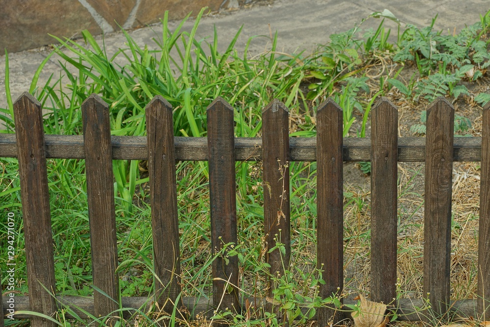Naklejka premium small brown decorative wooden fence in tall grass
