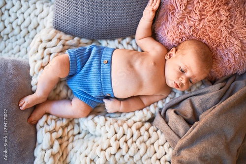 Adorable baby lying down on the sofa over blanket at home. Newborn relaxing and resting comfortable