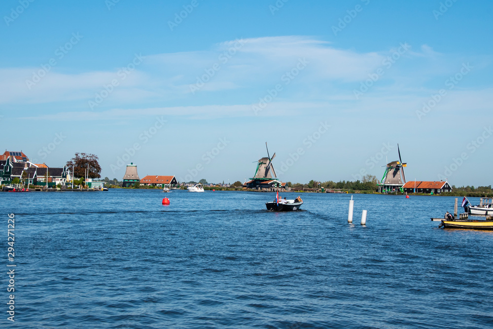 Obraz premium Zaanse Schans, Netherlands - 1 October 2019: Tourists sightseeng traditional Dutch rural houses in Zaanse Schans, is a typical small village within Amsterdam area.