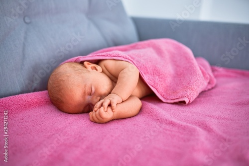 Adorable baby lying down on the sofa over blanket at home. Newborn relaxing and sleeping comfortable
