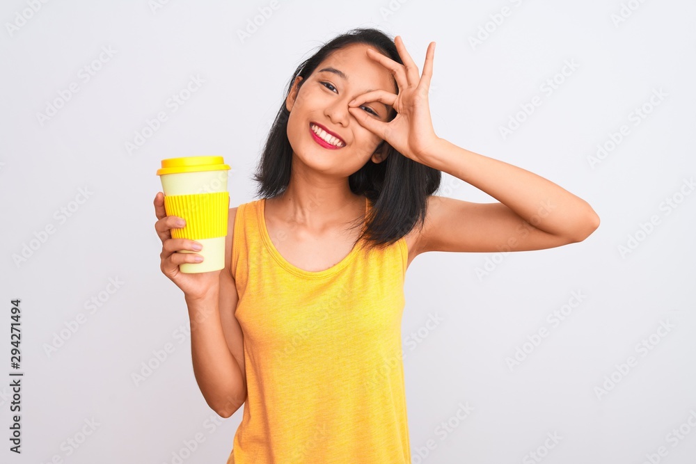 Young chinese woman drinking take away glass of coffee over isolated white background with happy face smiling doing ok sign with hand on eye looking through fingers Young chinese woman drinking take away glass of coffee over isolated white background with happy face smiling doing ok sign with hand on eye looking through fingers