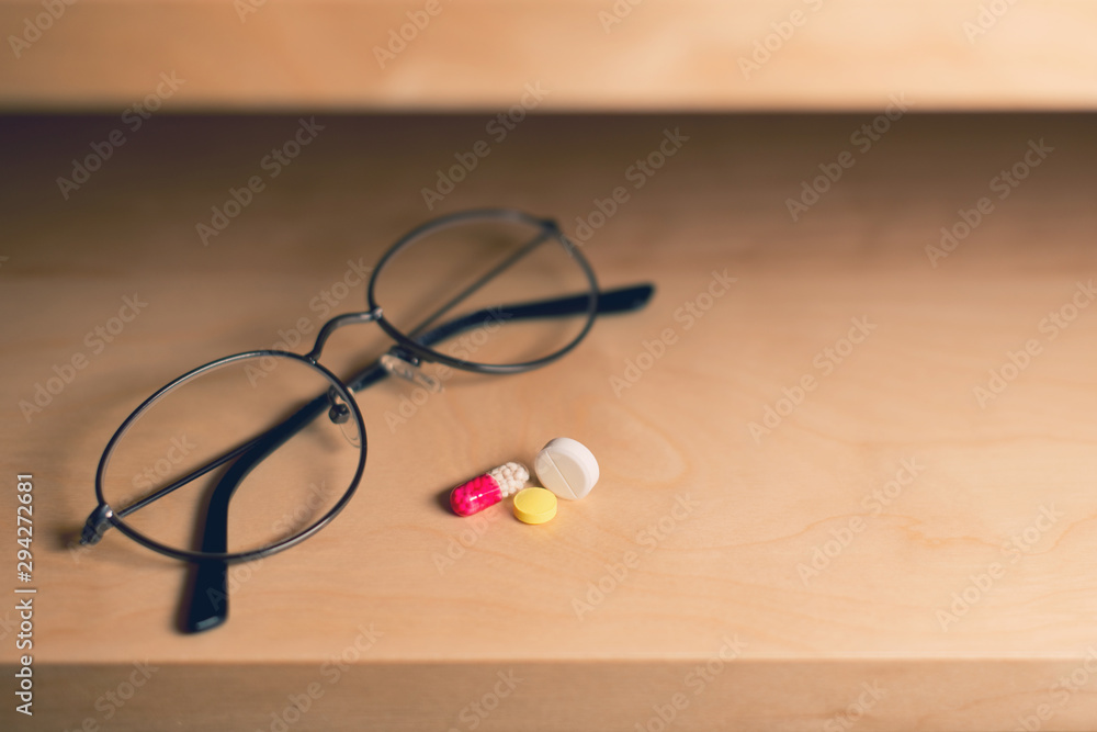 glasses for vision and tablets lies on a shelf glasses for vision and tablets lies on a shelf
