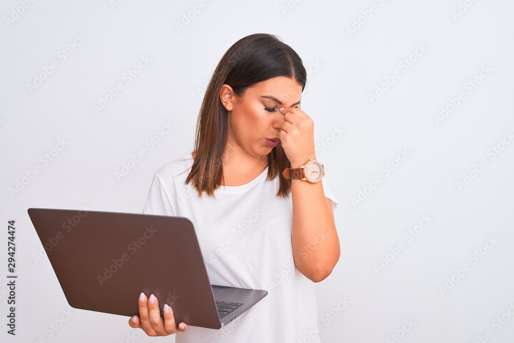 Beautiful young woman working using computer laptop over white background tired rubbing nose and eyes feeling fatigue and headache. Stress and frustration concept. Beautiful young woman working using computer laptop over white background tired rubbing nose and eyes feeling fatigue and headache. Stress and frustration concept.