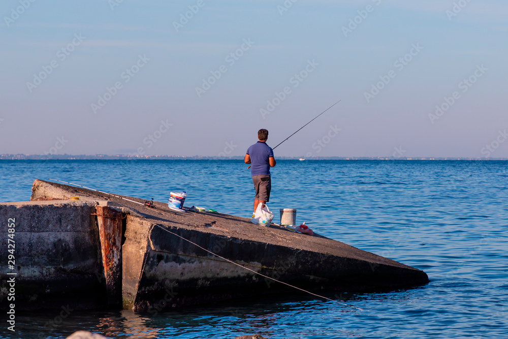 Fishing on a concrete boat ramp in Patras in Greece in the sunshine. Fishing on a concrete boat ramp in Patras in Greece in the sunshine.