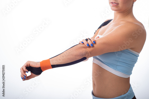 A female athlete puts a kineziotape on her wrist. Kineziology, alternative treatment for injuries of joints and tendons. Physiotherapy of chronic inflammation of the joints of a womans arm. photo