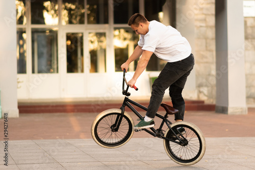 The guy rides on the BMX, standing on the rear wheel. © Artsiom P