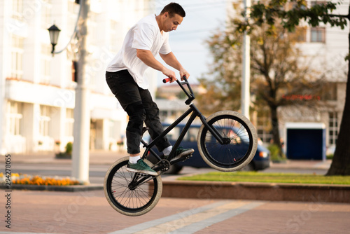 A young guy on a BMX bike, wraps the steering wheel in a jump.