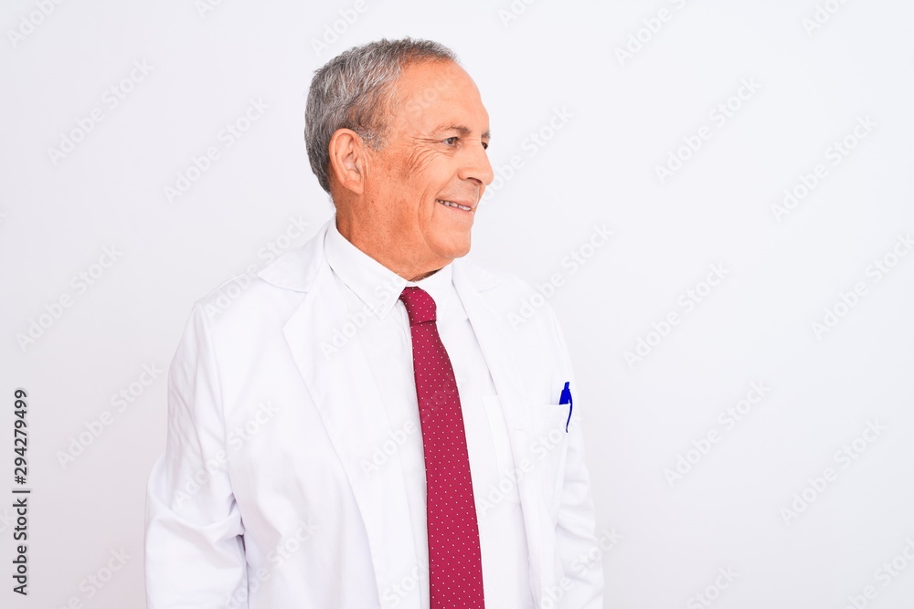 Senior grey-haired scientist man wearing coat standing over isolated white background looking away to side with smile on face, natural expression. Laughing confident. Senior grey-haired scientist man wearing coat standing over isolated white background looking away to side with smile on face, natural expression. Laughing confident.