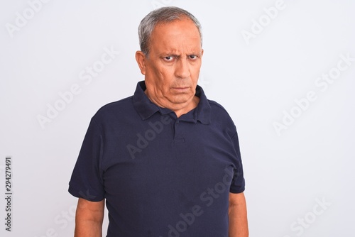 Senior grey-haired man wearing black casual polo standing over isolated white background skeptic and nervous, frowning upset because of problem. Negative person.