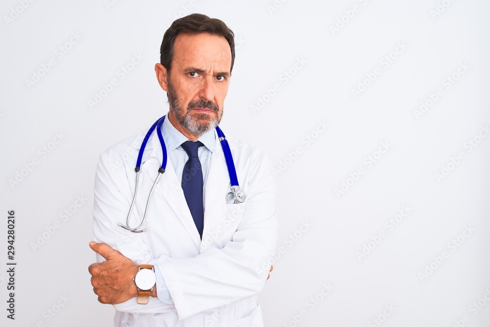Middle age doctor man wearing coat and stethoscope standing over isolated white background skeptic and nervous, disapproving expression on face with crossed arms. Negative person. Middle age doctor man wearing coat and stethoscope standing over isolated white background skeptic and nervous, disapproving expression on face with crossed arms. Negative person.