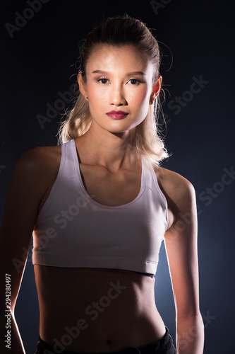 Asian slim Fitness woman exercise warm up stretch arms sport bra. Concept Woman Can Do athlete Sport healthy, studio lighting dark background with smoke backlit © Jade