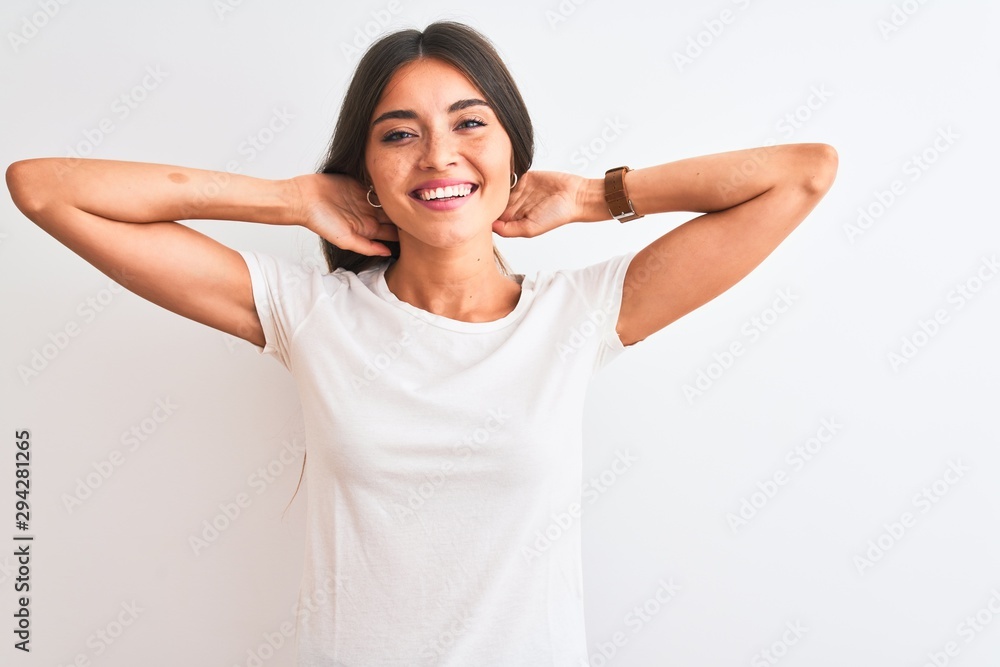 Young beautiful woman wearing casual t-shirt standing over isolated white background relaxing and stretching, arms and hands behind head and neck smiling happy Young beautiful woman wearing casual t-shirt standing over isolated white background relaxing and stretching, arms and hands behind head and neck smiling happy
