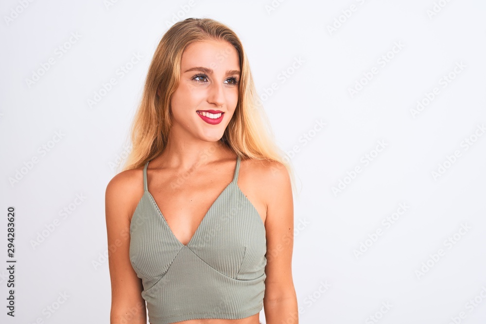 Young beautiful woman wearing casual green t-shirt standing over isolated white background looking away to side with smile on face, natural expression. Laughing confident. Young beautiful woman wearing casual green t-shirt standing over isolated white background looking away to side with smile on face, natural expression. Laughing confident.