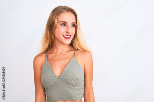 Young beautiful woman wearing casual green t-shirt standing over isolated white background looking away to side with smile on face, natural expression. Laughing confident. © Krakenimages.com