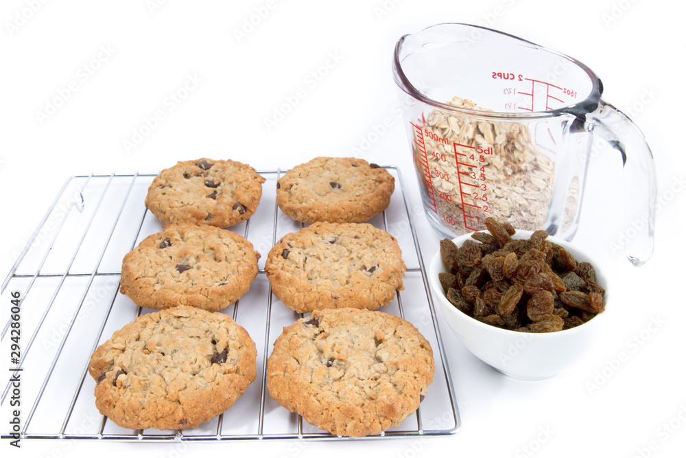 oatmeal raisin cookies on a rack with a measure of raisins and a measuring cup of rolled oats isolated on white oatmeal raisin cookies on a rack with a measure of raisins and a measuring cup of rolled oats isolated on white