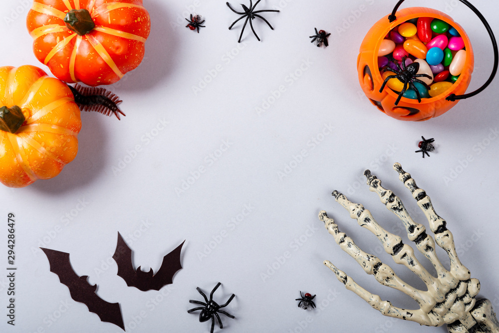 Fototapeta premium Halloween and decoration concept, Pumpkins, bats, skeleton arm and candies on gray background.