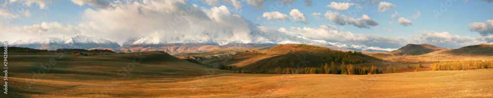 Autumn panoramic view, valley and snow-capped mountains in the clouds